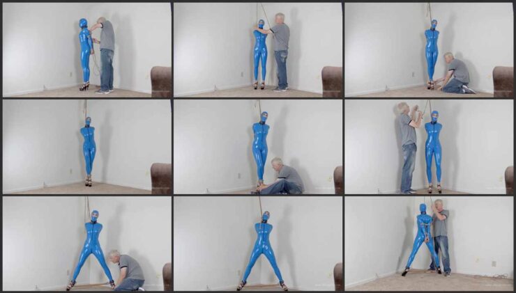 Arielle in latex blue catsuit cuffed to a spreader