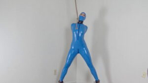 Arielle in latex blue catsuit cuffed to a spreader
