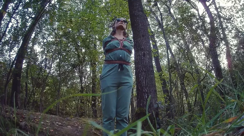 Sofi walking through the woods with his hands tied