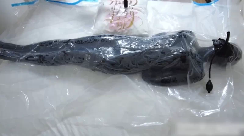 Asian girl bound in a leather bodysuit is confined inside a vacuum bag